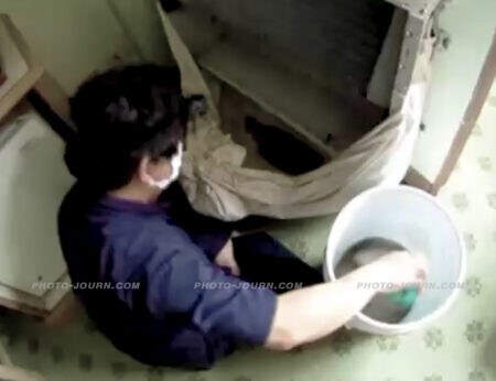 A worker filmed by 60 Minutes New Zealand hidden camera cleaning an air-conditioner in a fifth-floor room of The Downtown Inn, Chiang Mai. Freeze frame