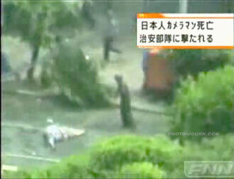 Japanese journalist Kenji Nagai holds his camera above his head as his murderer runs away