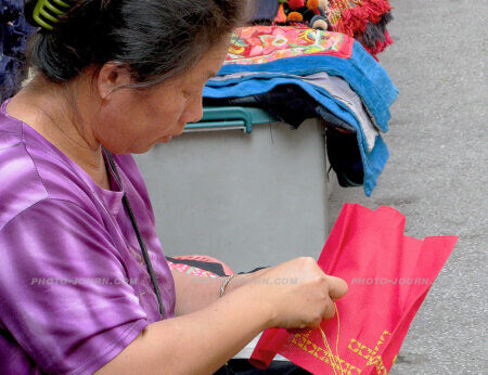 A woman embroiders an item of Hill Tribe clothing at Worarot Market