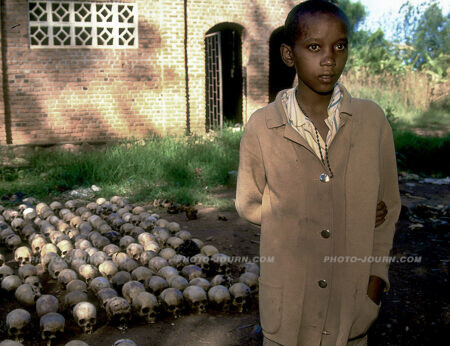 A 14-year-old boy, Rumanzi, photographed in June 1994 standing in front of rows of human skulls outside the Nitarama church near the town of Nyamata, where some 600 people were killed. Rumanzi survived the massacre by hiding beneath the corpses for two days.